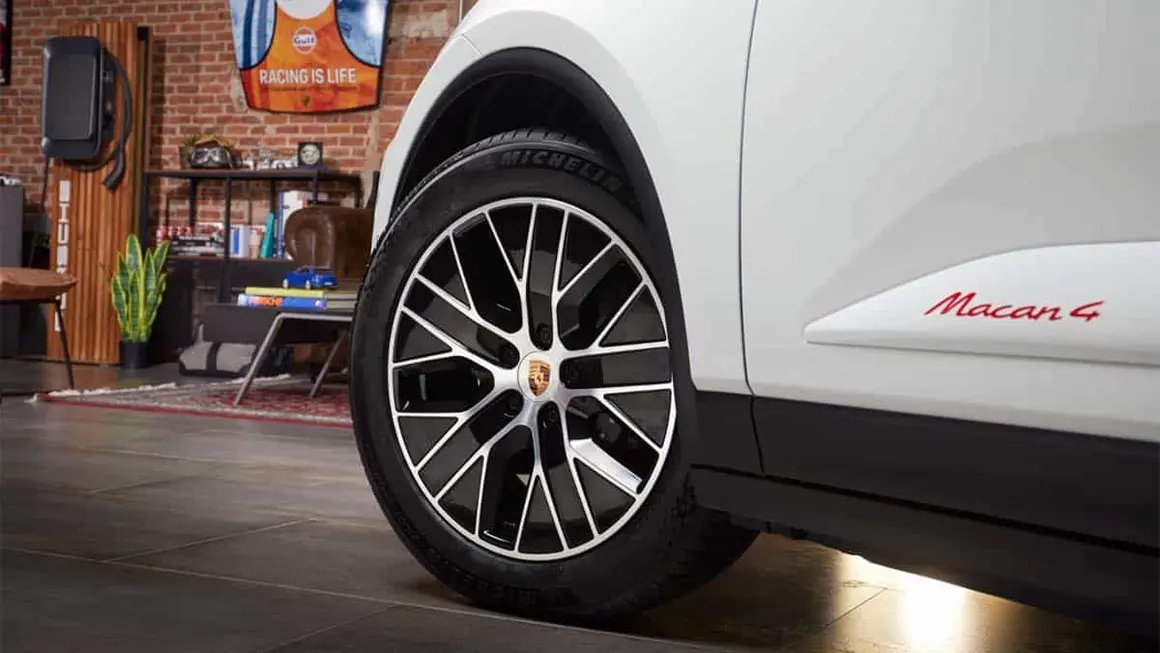 Imagen de un coche el&eacute;ctrico Porsche Macan G en un espacio de garaje, mostrando su rueda y dise&ntilde;o innovador.