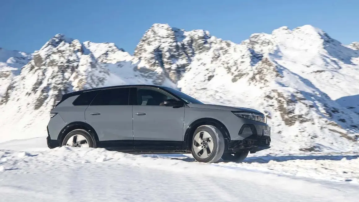 Coche el&eacute;ctrico en paisaje de monta&ntilde;a nevado, promoviendo movilidad ecol&oacute;gica y tecnolog&iacute;a innovadora.