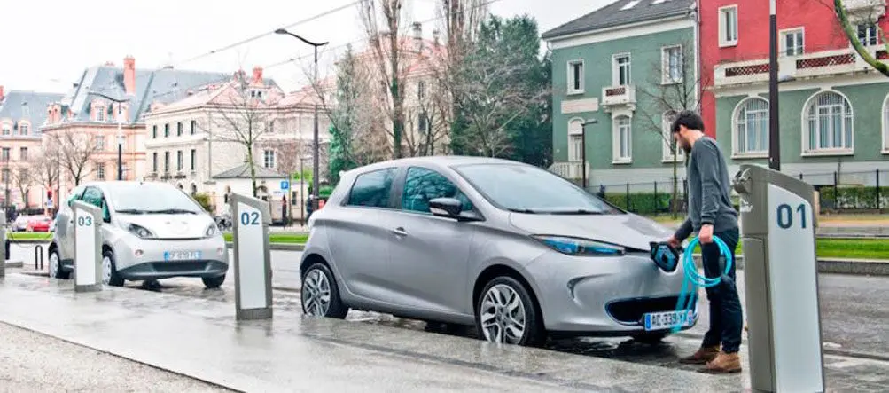 Coche el&eacute;ctrico cargando en un punto de recarga en la calle