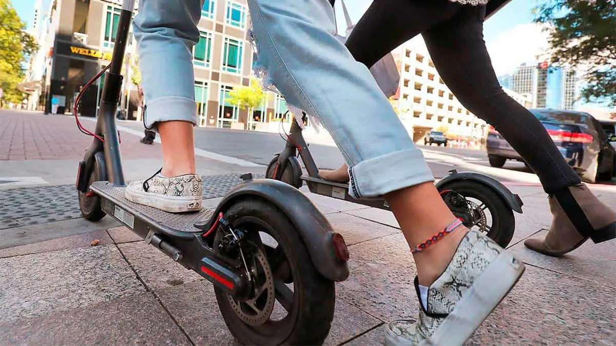 Varios patinetes el&eacute;ctricos siendo usado por dos chicas