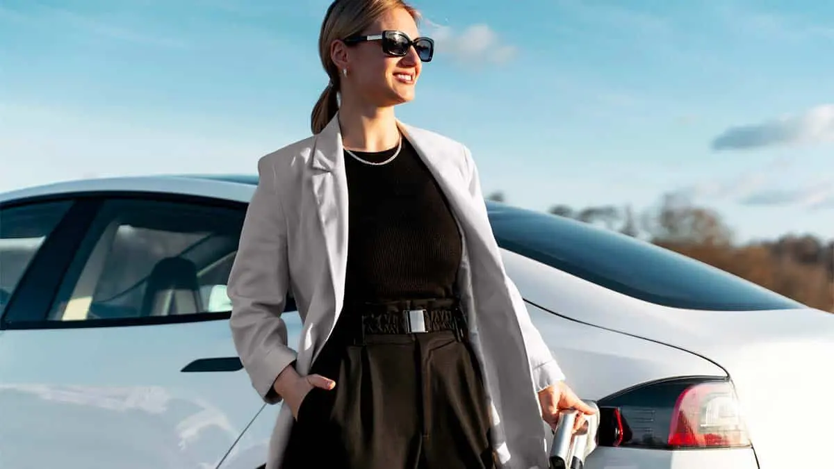 Mujer sonriente mientras carga su coche Tesla
