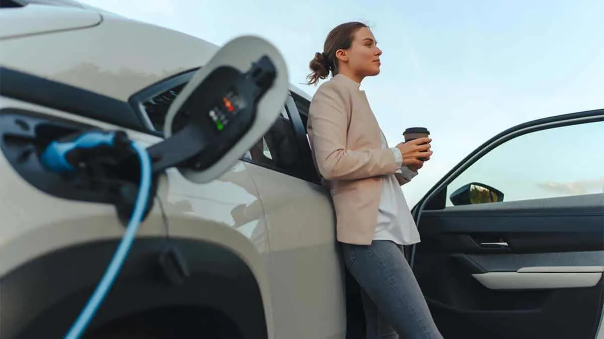 Chica esperando mientras carga coche el&eacute;ctrico