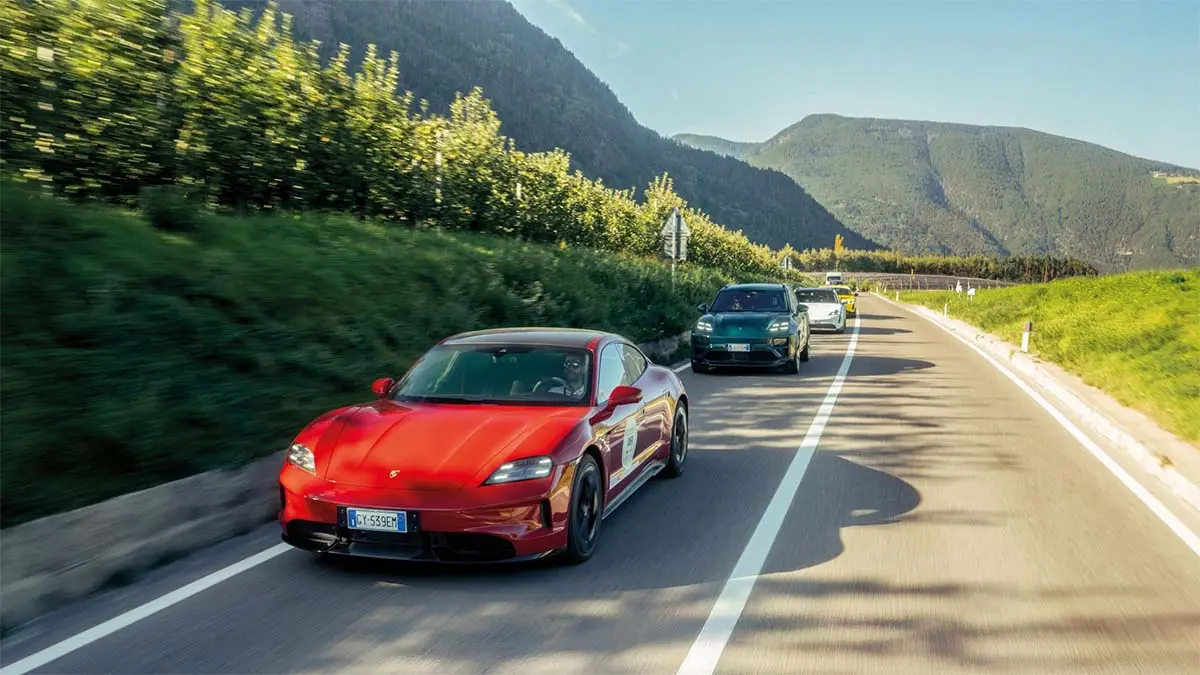 Imagen de varios coches el&eacute;ctricos deportivos en movimiento en una carretera rodeada de naturaleza.