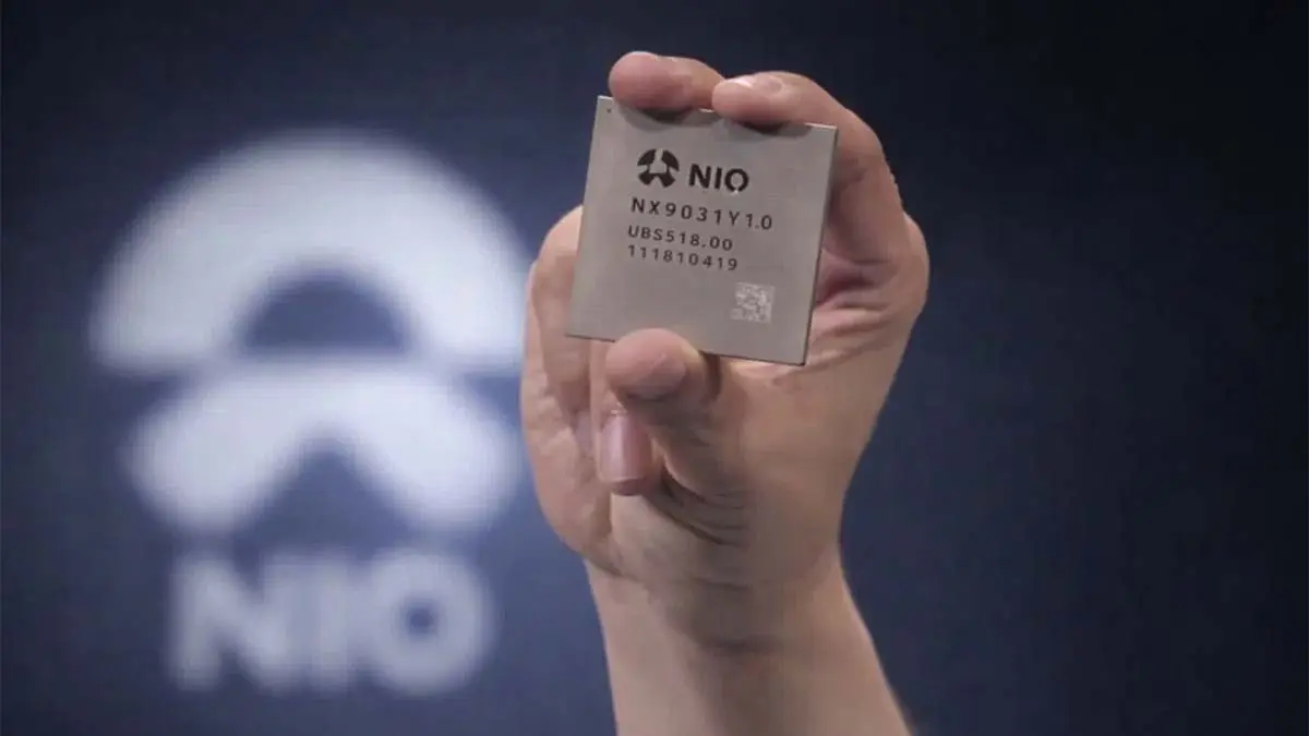 La imagen muestra una mano que sostiene un chip de NIO, destacando su apuesta por la innovaci&oacute;n en tecnolog&iacute;a de coches el&eacute;ctricos.