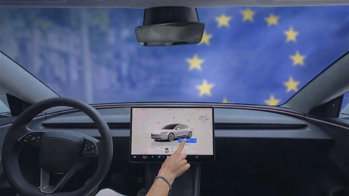 Interior de un Tesla Model 3 con pantalla t&aacute;ctil y bandera de la Uni&oacute;n Europea, destacando la pr&oacute;xima disponibilidad del FSD en Europa.