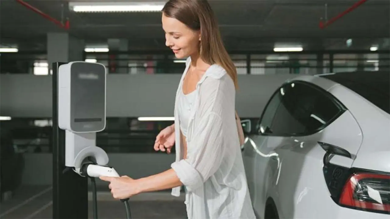 Chica conectando cable de carga en Tesla Model 3