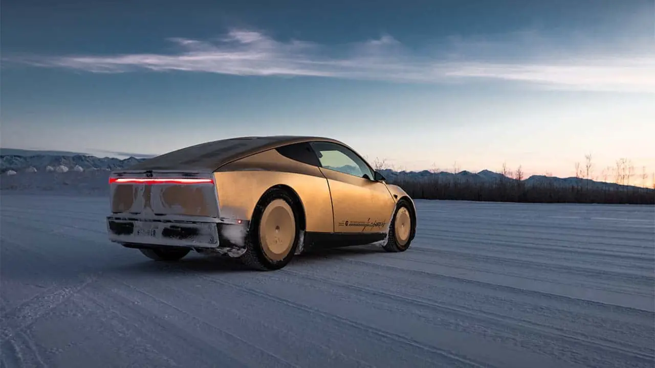 Veh&iacute;culo el&eacute;ctrico futurista movi&eacute;ndose sobre nieve en un paisaje invernal al atardecer, destacando innovaci&oacute;n sostenible.
