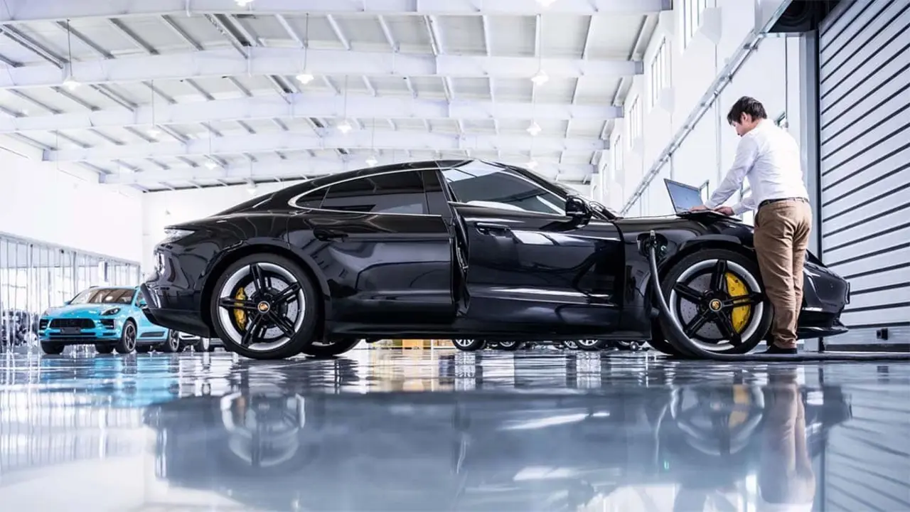Un coche el&eacute;ctrico negro en un taller de alta tecnolog&iacute;a con un t&eacute;cnico realizando diagn&oacute;sticos.