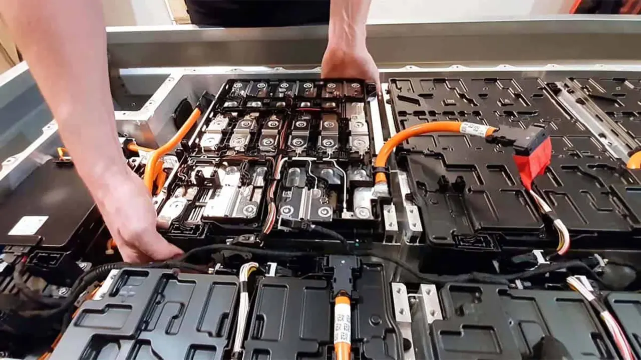Bater&iacute;a de coche el&eacute;ctrico en proceso de reparaci&oacute;n, con cables y componentes abiertos.