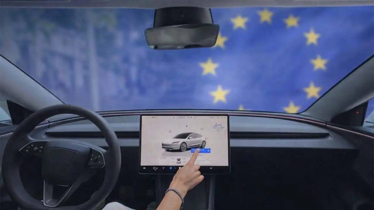 Interior de un Tesla Model 3 con pantalla t&aacute;ctil y bandera de la Uni&oacute;n Europea, destacando la pr&oacute;xima disponibilidad del FSD en Europa.