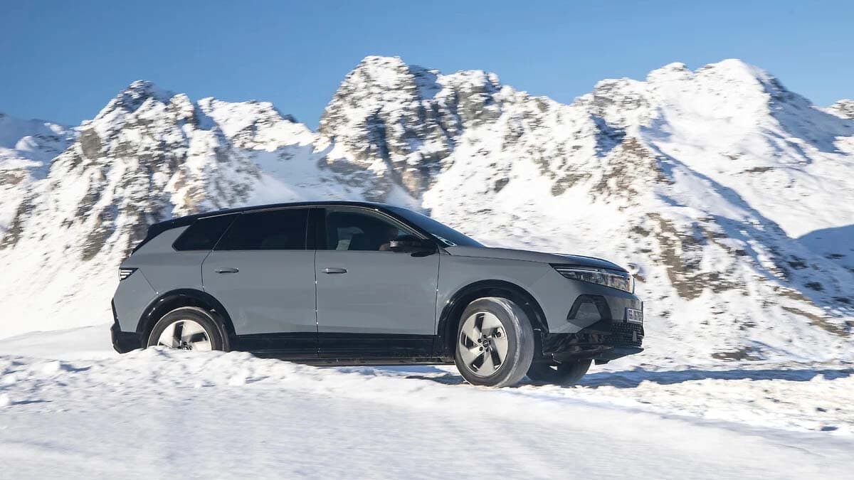 Coche eléctrico moderno conduciendo en paisaje nevado con montañas. Vehículo ecológico para movilidad sostenible.