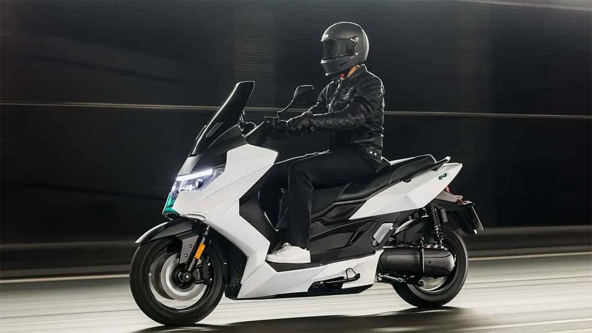 Motociclista en moto eléctrica con casco y chaqueta de cuero, desplazándose por túnel.