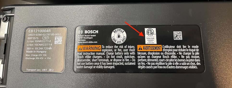 Etiqueta de seguridad y advertencias en la batería de un coche eléctrico Bosch con detalles técnicos visibles.