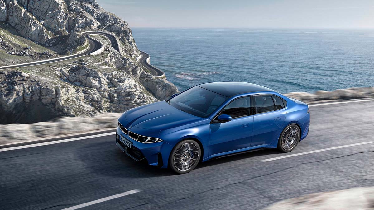 Nuevo BMW i3 2026 en carretera junto al mar, diseño moderno y aerodinámico.